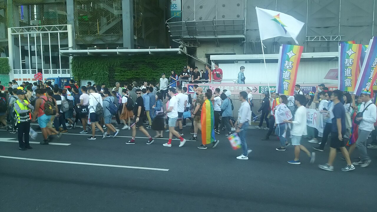 Marchers with rainbow flags walking past Taipei Main Station during Taiwan LGBT Pride